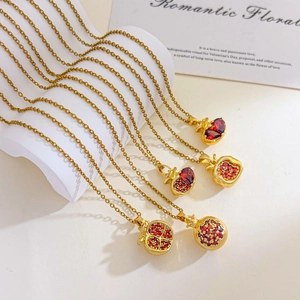 Elegant 18K gold-plated pomegranate necklaces with red zircon stones on a white stand