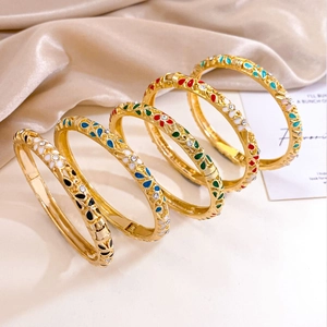Five gold-plated enamel flower bangles with rhinestones on elegant silk background