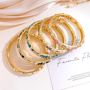 Vintage gold plated bangle set with colorful enamel flowers and shimmering rhinestones