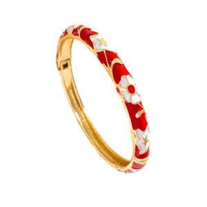 Elegant gold-tone bangle featuring red enamel with white flowers and star patterns