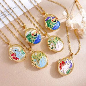 Golden oval locket necklaces with colorful enamel rabbit and swan designs on textured backdrop