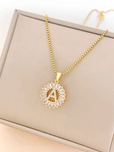 Macro detail of gold necklace with a sunburst A letter pendant and box chain