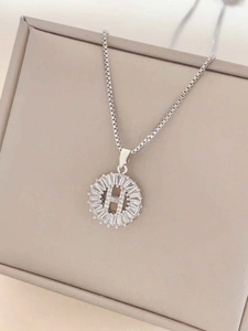 Macro shot of a silver letter H pendant necklace with baguette-cut zircon gemstones