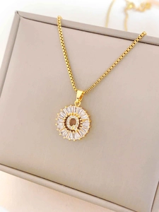 Macro shot of gold sunburst pendant with letter Q and sparkling zircon stones