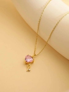 Close-up of pink heart gemstone and gold key pendant on a dainty stainless steel chain