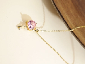 Close-up of heart-shaped pink gem necklace with gold key and heart charms