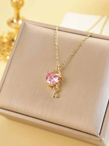 Detail of pink heart crystal necklace with gold key pendant on champagne jewelry box