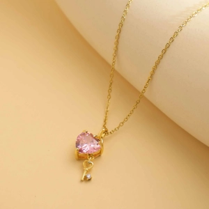 Elegant gold titanium steel necklace featuring a pink heart gem and a golden key pendant