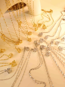 Nahaufnahme von Herz- und Blumenketten in Gold und Silber mit weißen Edelsteinen