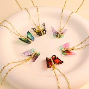 Detailed view of colorful resin butterfly necklaces with crystals in a white ceramic tray