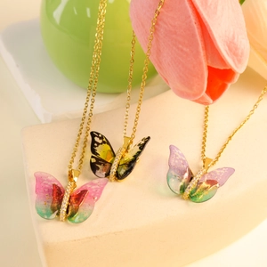 Colorful butterfly pendant necklace set with gradient wings and gold chain on stone