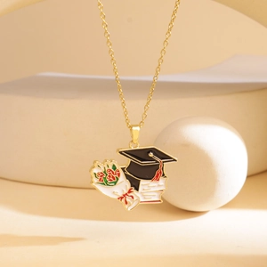 Golden graduation necklace with black mortarboard and red rose pendant on beige backdrop