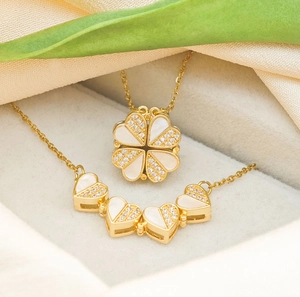 Detail of gold clover heart necklace showing magnetic folding mechanism and pearl inlays