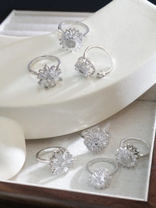 Detailed view of six silver rings with rotating flower designs and zircon crystals