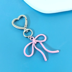 Pink metallic bow keychain with silver heart clasp on vibrant blue background