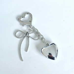Polished metal bow and heart keychain charm with a silver-finish snap hook detail
