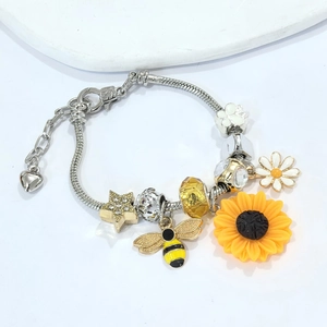 Detail of sunflower and bee charms on silver snake chain bracelet with heart clasp