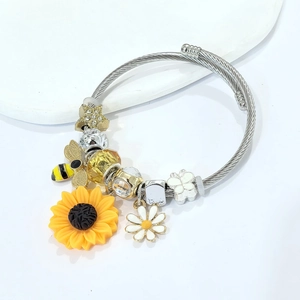 Detail view of sunflower, bee and star charms on a braided stainless steel cable bracelet
