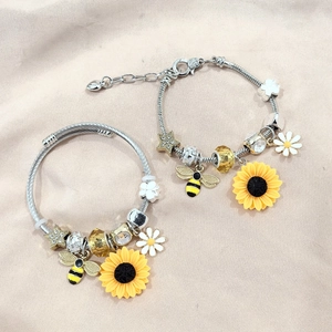 Detailed view of silver charm bracelet and bangle with sunflower and bee pendants