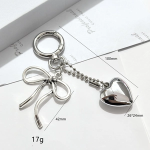 Detailed view of silver bow and heart keychain showing size and metal texture