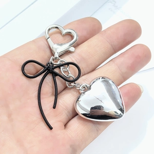 Detail of silver heart keychain with black ribbon bow and heart spring clasp