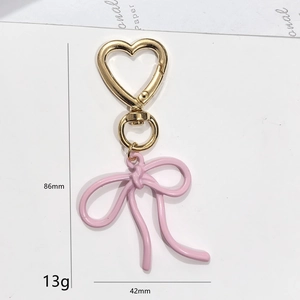 Détail d'un porte-clés nœud rose avec crochet cœur doré et dimensions précises