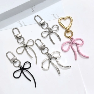 Detailed macro view of metal bow keychains in silver, black, and pink enamel finishes