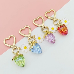 Detail of four colorful resin strawberry keychains with heart-shaped gold clasps