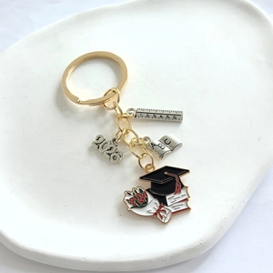 Macro detail of 2026 graduation keychain featuring mini book, ruler and scholar cap charms