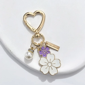 Detail of flower enamel pendants and heart carabiner on a gold-tone handmade keychain
