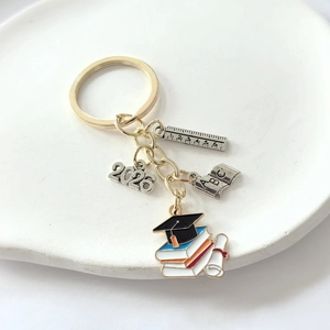 Golden 2026 graduation keychain featuring doctor hat, ABC book, and ruler pendants