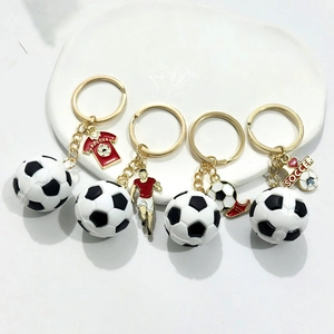 Détail de quatre porte-clés de football dorés avec charms maillot et ballon sur plateau