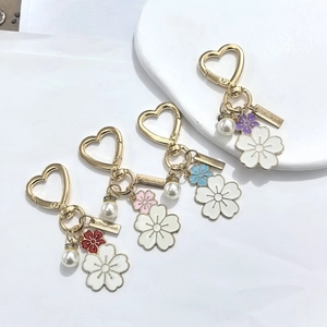 DIY flower keychain with gold heart clasp, white enamel petals, pearls and handmade charm