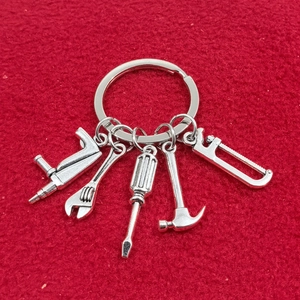 Ensemble porte-clés 5 outils en métal argenté comprenant marteau et clé sur fond rouge