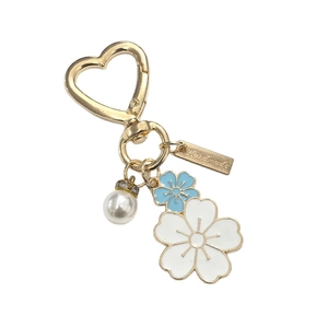 Chic floral pearl keychain with blue enamel flower and gold heart clasp on white background