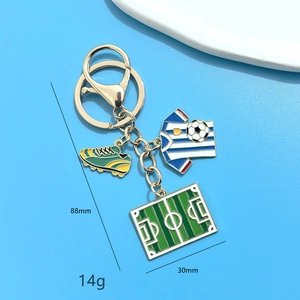 Football souvenir keychain with gold soccer ball, jersey, shoe, and field charms