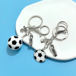 Détail de porte-clés football avec breloques ballon 3D et chaussure sur plateau blanc