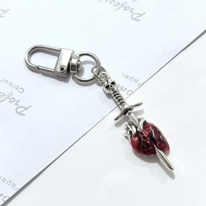 Détail macro d'une épée gothique avec crâne perçant un cœur rouge sur porte-clés