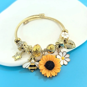 Detailed view of gold steel bangle with daisy, bee, sunflower charms and yellow crystal beads