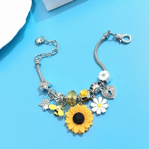 Detail of silver snake chain bracelet featuring yellow sunflower and bee charms