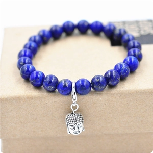 Primer plano de pulsera de cuentas de lapislázuli con dije de buda plateado sobre caja