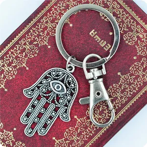 Detailed close-up of a silver Hamsa hand keychain with an evil eye on a vintage book