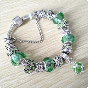 Detail of green crystal beads and silver snake chain bracelet with floral spacers