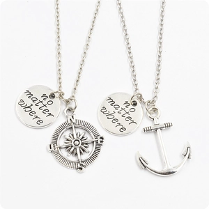 Close-up of no matter where engraved tags with compass and anchor pendants