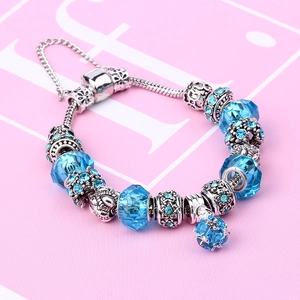 Detail of silver snake chain bracelet with blue glass beads and crown charms