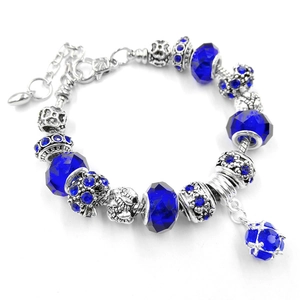 Bracciale vintage con perline di cristallo blu e ciondoli in argento su sfondo bianco