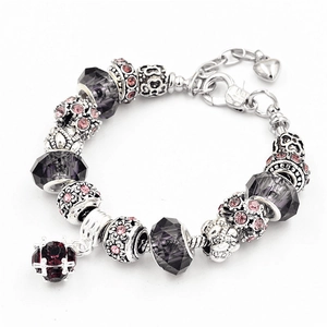 Dettaglio macro del bracciale con ciondoli argento, perle di vetro viola e cristallo