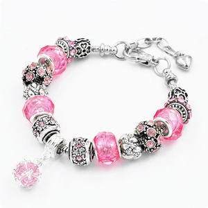 Dettaglio di ciondoli in cristallo rosa e perline di vetro su bracciale a serpente