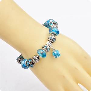 Dettaglio del bracciale con ciondoli, perle di cristallo blu e pendenti argentati