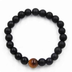 Close-up of matte black agate beads with a polished tiger eye stone on a men's bracelet